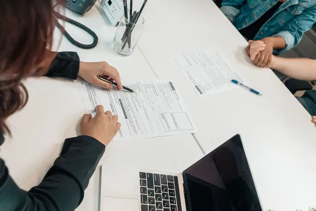 A professional meeting with document signing at an office desk, focusing on teamwork. EIN applications: planning, execution and measurement