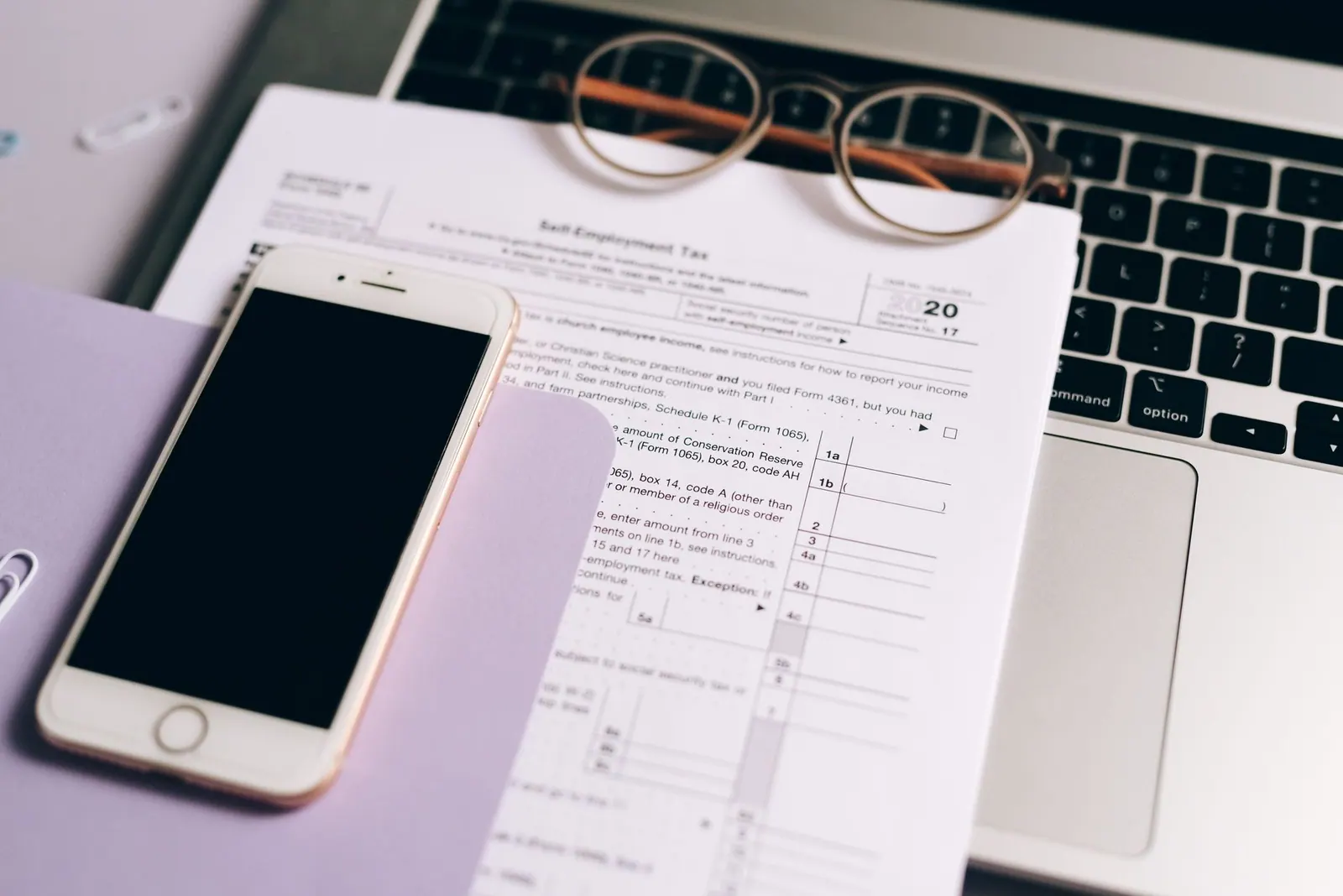 Close-up of tax documents with laptop and smartphone on a desk. EIN applications checklist: 12 points to review in 2027