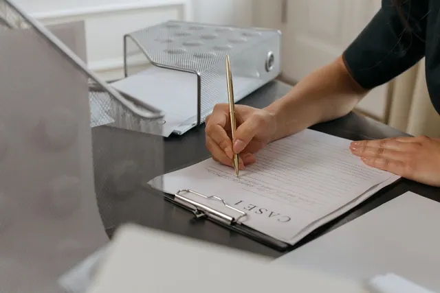 Close-up of a woman writing on documents with a gold pen in an office environment. Entity type selection case study: findings and lessons