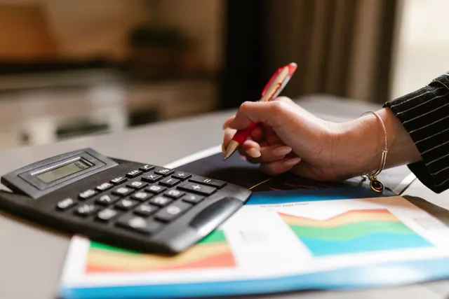 A business professional uses a calculator and documents during a workspace task. Entity type selection metrics: facts, examples and context