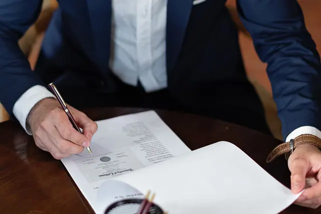 A professional individual signs legal documents at a desk in an office setting. Partnership formation: what beginners should know