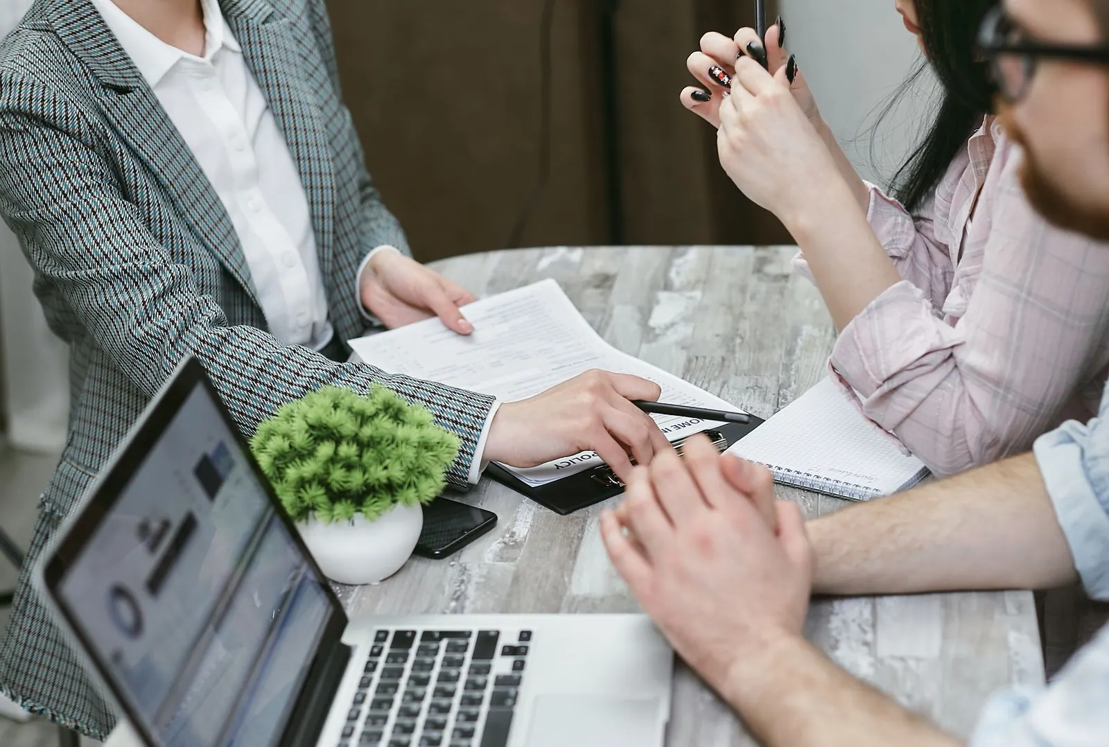 Professional meeting discussing business agreements with laptops and documents on a rustic table. Partnership formation questions explained with examples